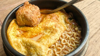 Noodle soup with egg in black bowl on wooden table