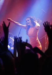 Fototapeta na wymiar People hands, singer woman and concert at night performance, singing and gen z in lights, celebration or cheers. Musician person on stage and microphone at event with fans, crowd or audience dancing