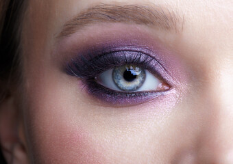 Obraz premium Closeup macro shot of human female eye. Woman with lilac beauty eyes makeup.