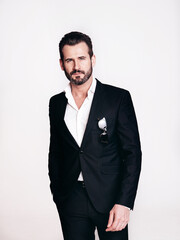 Portrait of handsome confident stylish hipster lambersexual model. Sexy modern man dressed in black elegant suit. Fashion male posing in studio, isolated on white