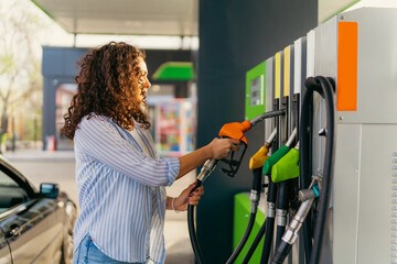 Young woman with curly hair refueling car at a self service gas station