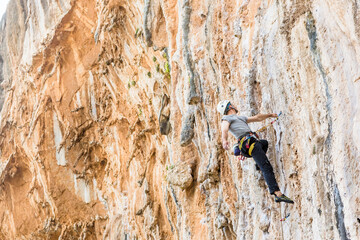 Fototapeta premium Young male climber hanging by a cliff