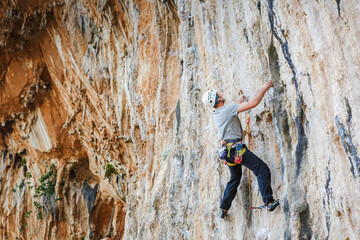 Young male climber hanging by a cliff