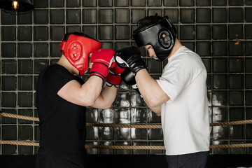 Two big guys boxing and sparring in the ring in head guard helmets and gloves.