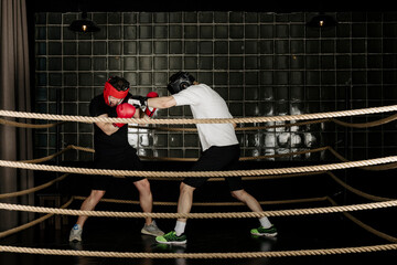 Two big guys boxing and sparring in the ring in head guard helmets and gloves.