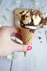 
Vanilla chocolate ice cream cone. On a white wooden background. Sweets