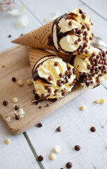 
Vanilla chocolate ice cream cone. On a white wooden background. Sweets