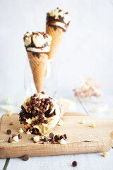 
Vanilla chocolate ice cream cone. On a white wooden background. Sweets