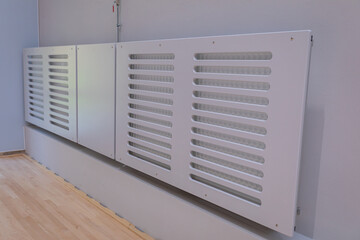 Panel radiators encased in a grille with longitudinal openings in the sports hall .