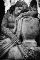 Ancient statue of angel with extinguished torch down as symbol of death and the end of human life. Black and white image.