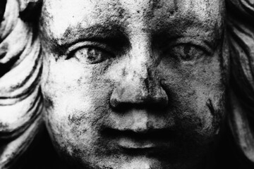Macro image of angel as symbol of pain, fear and end of life. Fragment of an ancient statue.