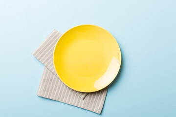 Top view on colored background empty round yellow plate on tablecloth for food. Empty dish on napkin with space for your design