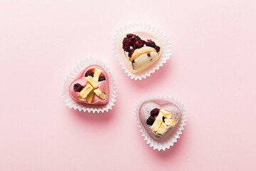 chocolate sweets in the form of a heart with fruits and nuts on a colored background. top view with space for text, holiday concept