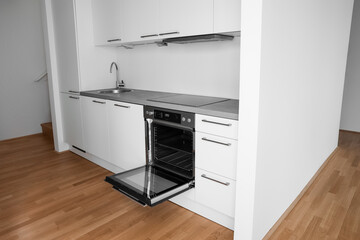 Interior of modern kitchen with white counters, sink and oven