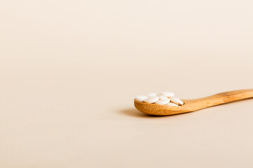 Heap of white pills on colored background. Tablets scattered on a table. Pile of red soft gelatin capsule. Vitamins and dietary supplements concept