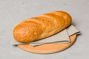 Freshly baked bread on cutting board against white wooden background. perspective view bread with copy space
