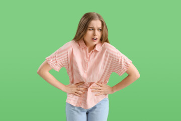Young woman with appendicitis on green background