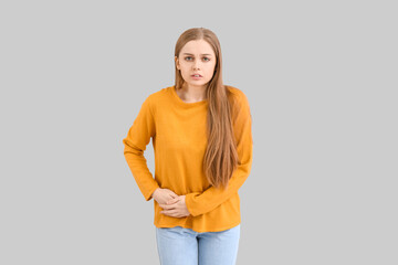 Young woman with appendicitis on grey background