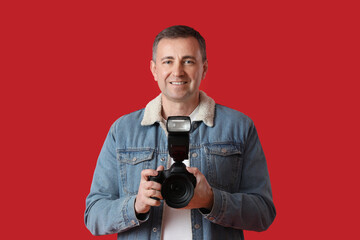 Fototapeta premium Mature photographer with professional camera on red background