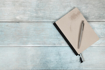 Retro notebook with pen above blue wooden planks background