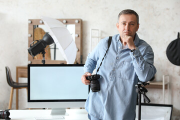 Mature photographer with professional camera and computer in studio
