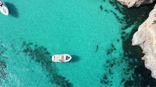 Drone view of white boat floating on turquoise water of Blue Lagoon, Comino Island Malta, Mediterranean sea. Summer boat trip