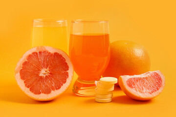 Glass of vitamin C effervescent tablet dissolved in water and grapefruits on orange background