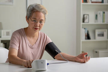 Asian senior woman measuring blood pressure at home - 596594669