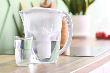 Modern filter jug and glass of water on kitchen counter