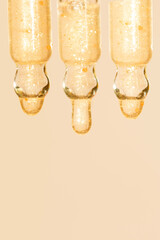 close up of a pipette droppers with pouring face serum on a beige background