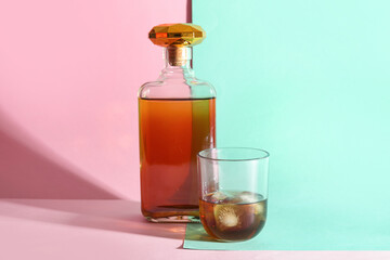 Glass and bottle of rum with ice cubes on colorful background