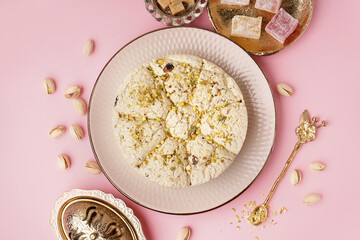 Plate of tasty Tahini halva with pistachios on pink background