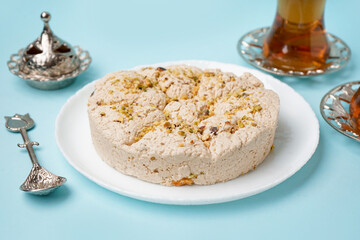 Plate of tasty Tahini halva with pistachios on blue background