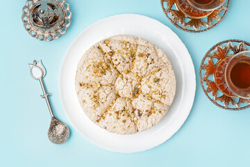 Plate of tasty Tahini halva with pistachios on blue background