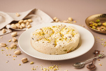 Plate of tasty Tahini halva with pistachios on beige background