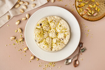 Plate of tasty Tahini halva with pistachios on beige background