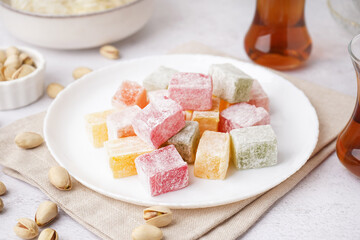 Plate with tasty Turkish Delight on light background