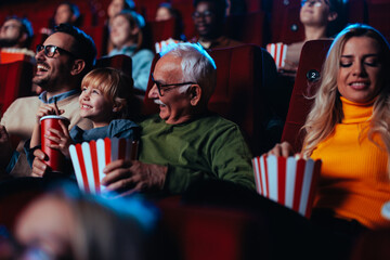 Cheerful mature man with granddaughter at movies.