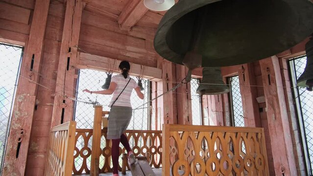 Christian Voznesenskiy Cathedral in the center of Almaty city. Orthodox christian church. The bell tower of the Cathedral. Bell ringer a woman rings the bells. Panfilov park. 4k footage