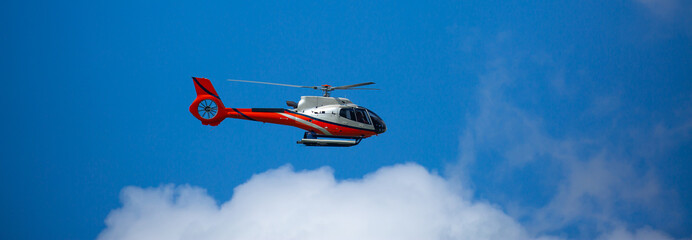 Rescue helicopter flies in the sky among the clouds. Red-white Helicopter. © Vera