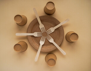 A paper plate and five wooden forks and cups, top view. Eco waste. Flat lay, copy space.