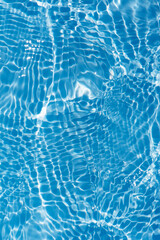 Blue water with ripples on the surface. Defocus blurred transparent blue colored clear calm water surface texture with splashes and bubbles. Water waves with shining pattern texture background.