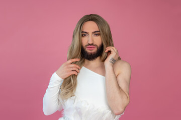 Beautiful transgender wearing blonde wig and white dress looking at camera with confident expression