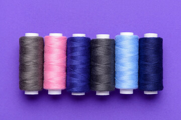 Set of different thread spools on purple background