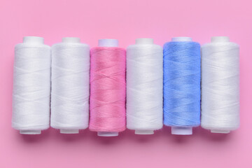 Set of different thread spools on pink background