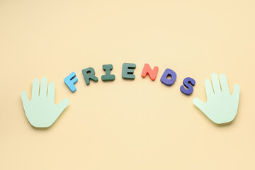 Paper palms and word FRIENDS on beige background. Friendship Day celebration
