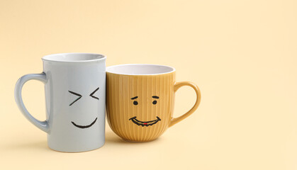 Cups with happy faces for Friendship Day on beige background