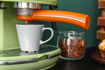 Modern coffee machine with cup on black table, closeup