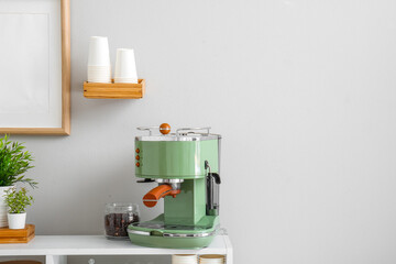 Modern coffee machine, jar with beans and houseplants on table near white wall