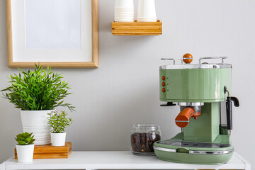Modern coffee machine, jar with beans and houseplants on table near white wall
